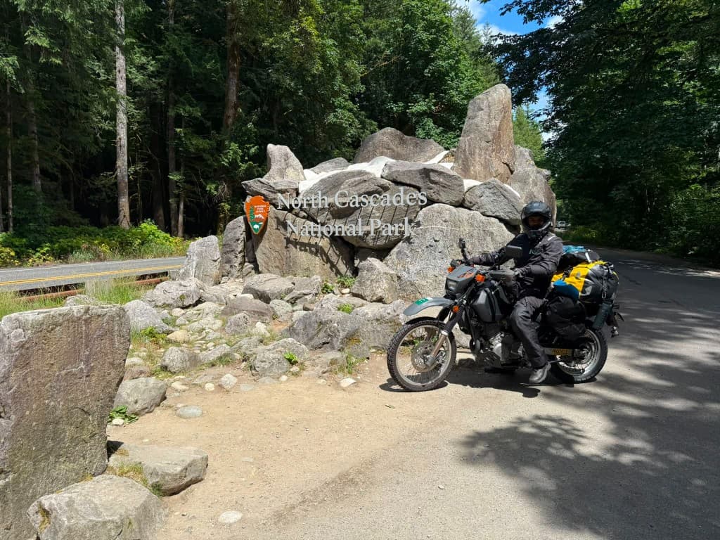 North Cascades National Park entrance arch with loaded Suzuki DR650