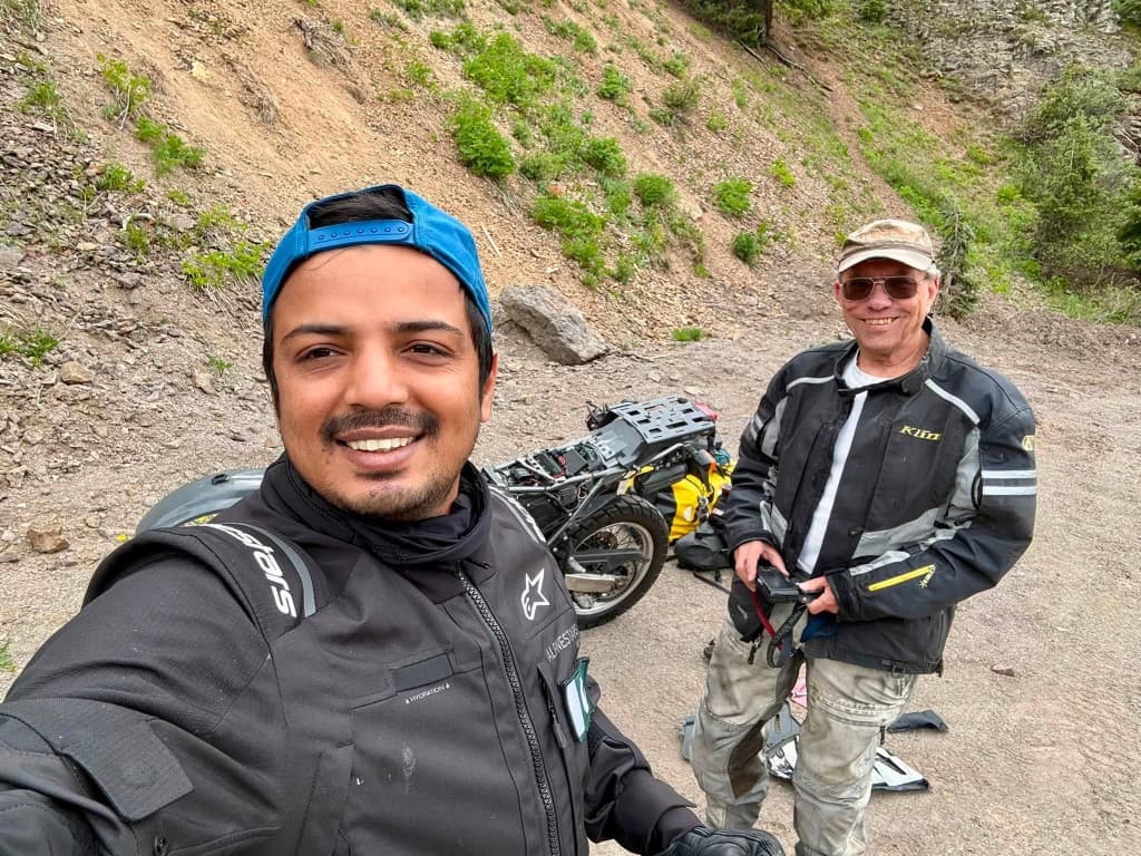 Two adventure riders meeting on a forest trail during a maintenance stop