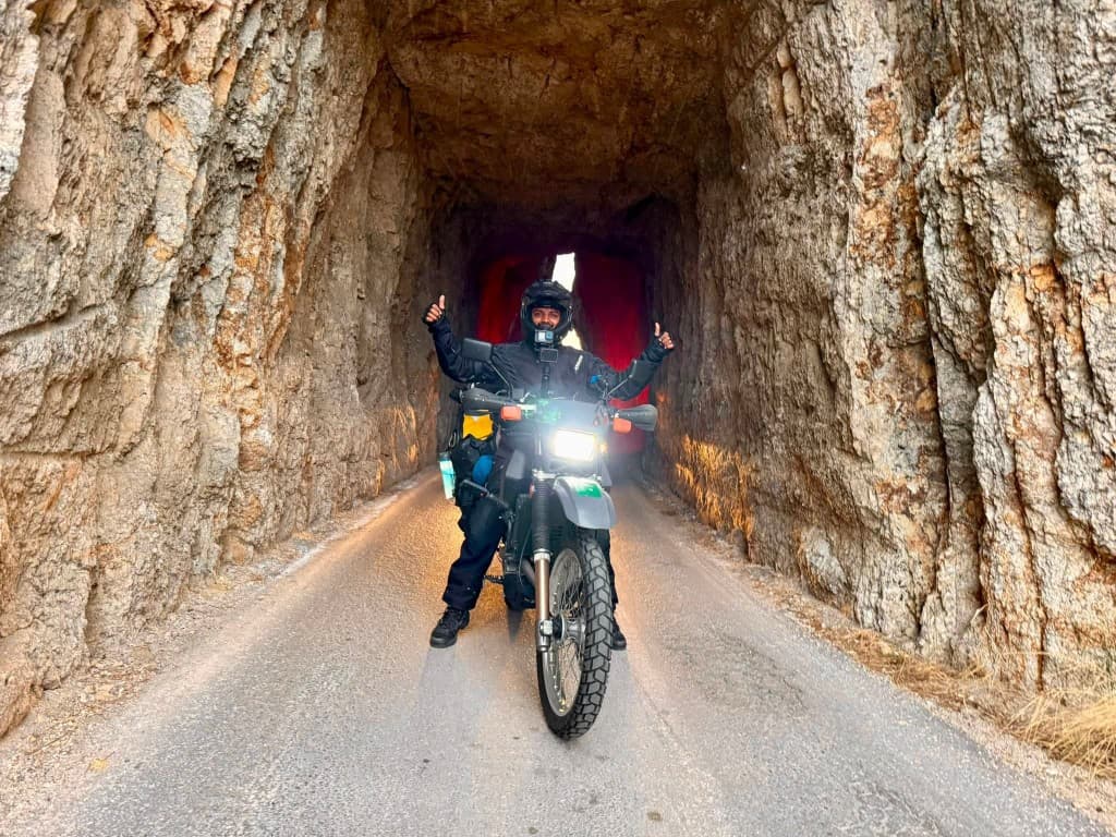 Rider giving double thumbs up inside a hand-carved rock tunnel