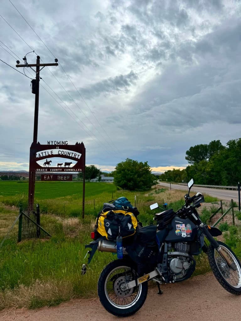 Loaded DR650 beside Wyoming cattle country roadside sign
